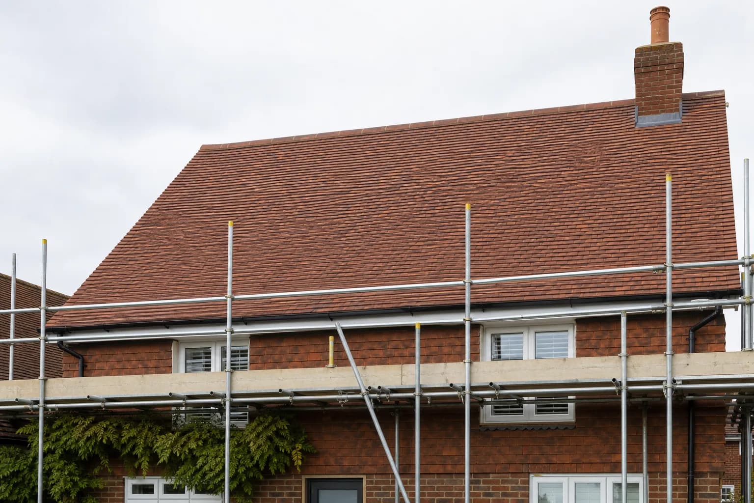 Freshly tiled pitched roof on a Kent house with scaffolding along the eaves