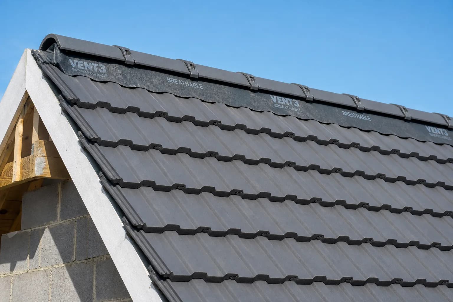 A new tiled pitched roof being installed with interlocking tiles and breathable membrane at the ridge